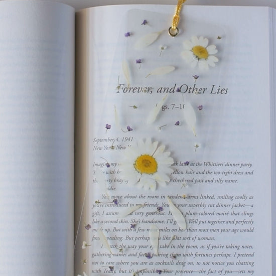 Video de separador de libros transparente con flores prensadas en su interior de color blanco.