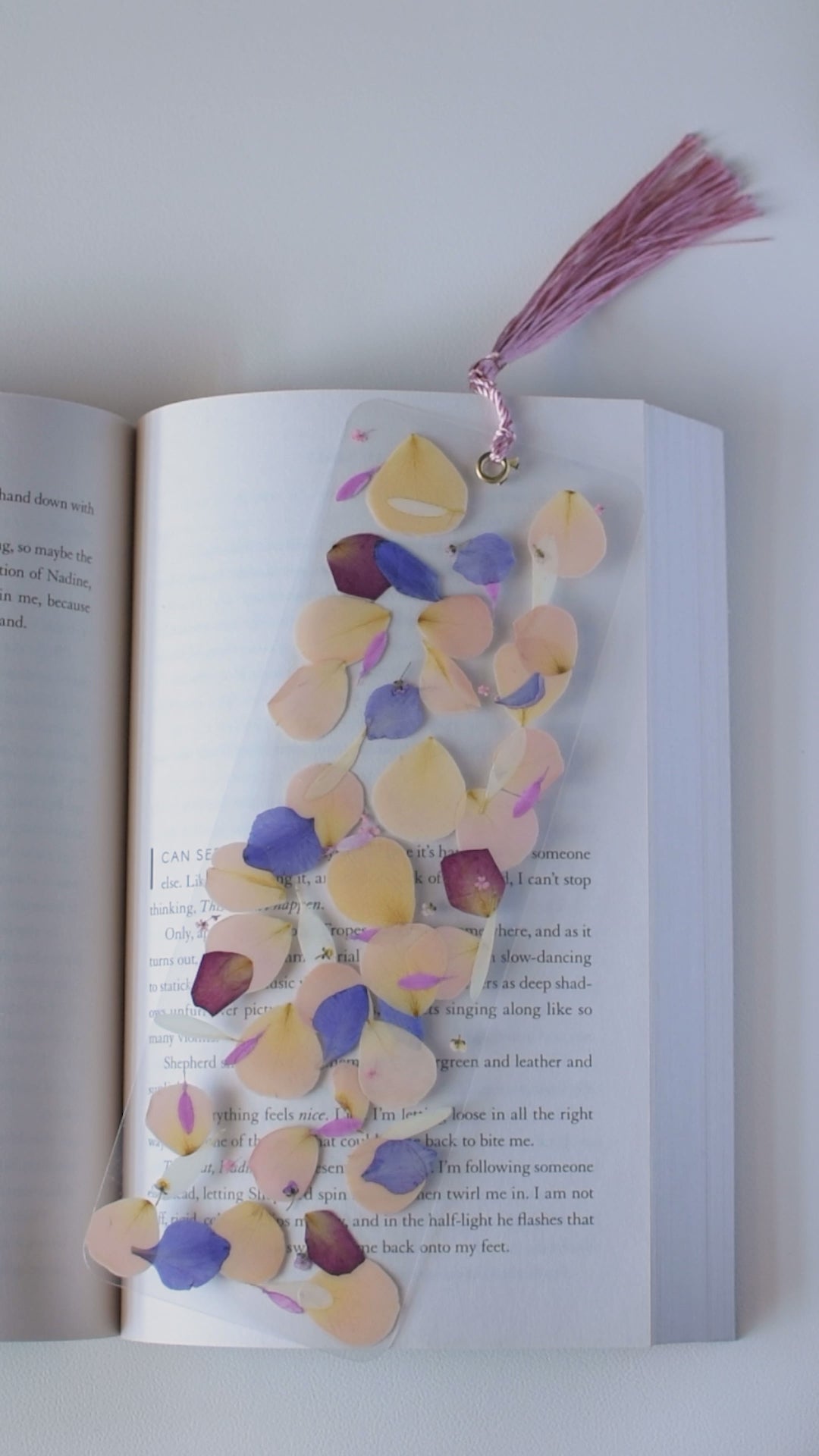 Video de separador de libros transparente con pétalos prensados en su interior de color rosa.