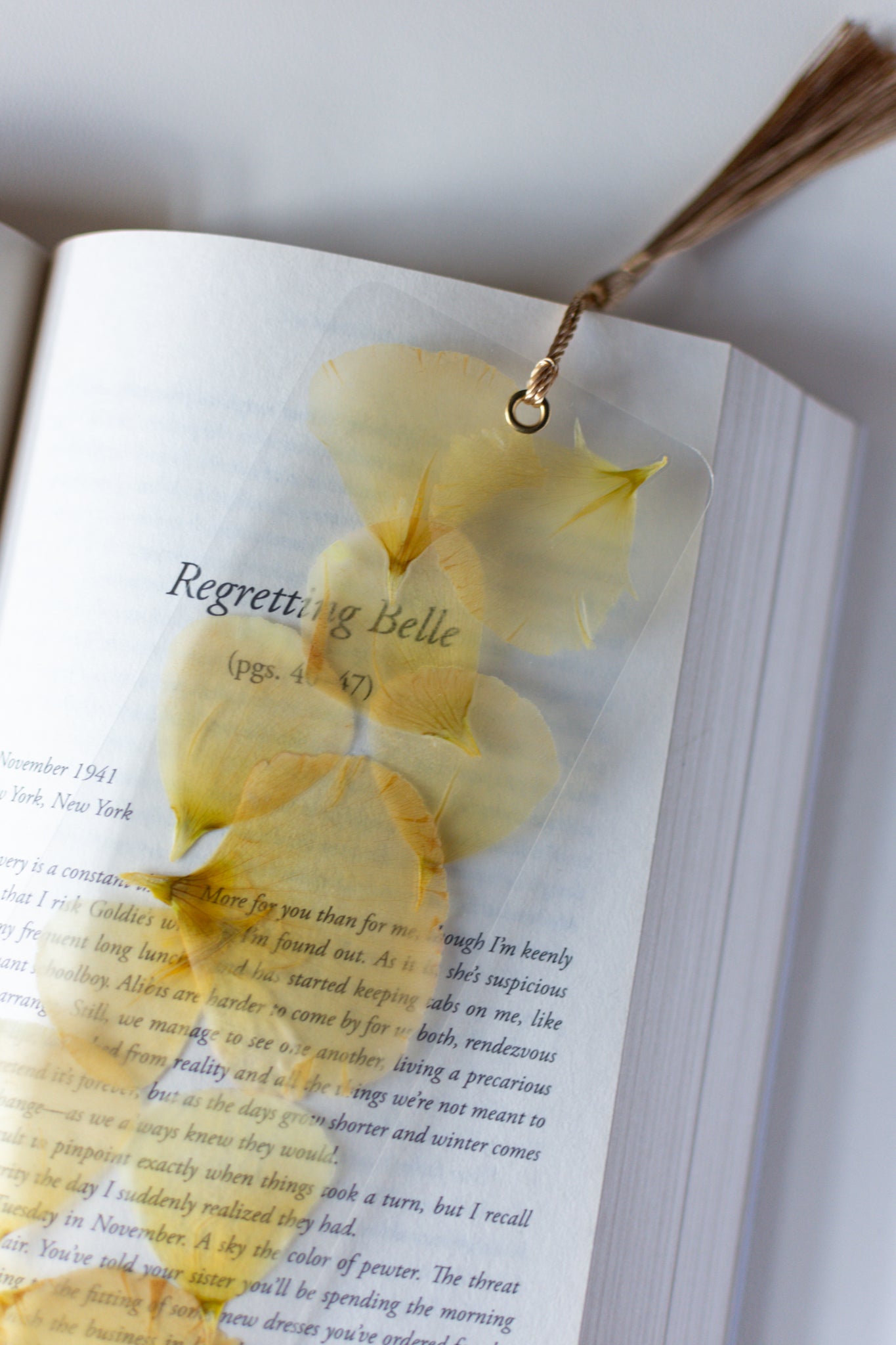 Separador de libros transparente con pétalos prensadas en su interior de color blanco.